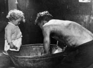 17. Miner washing at home in tin bath