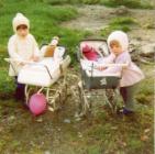 Two young girls playing with toy prams