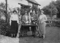 Five lady golfers with golf clubs and a trophy,...