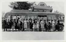 Photograph of a Group of People in Front of a Bus.