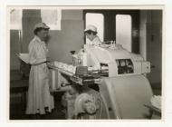 Two women workers with a butter packing machine...