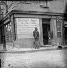 Unknown man standing outside grocer A. I....