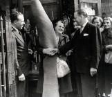 Woman holding carpet speaking to shop manager